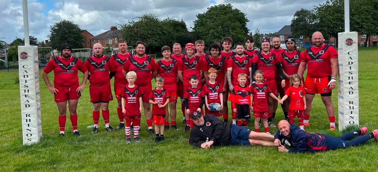 Cadishead Rhinos players and young supporters on the rugby pitch