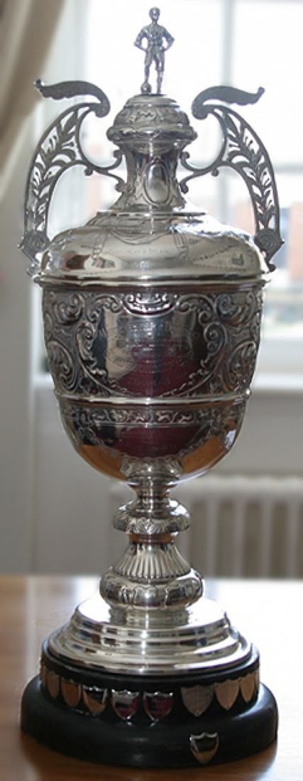 The Valentine Cup trophy, with ornate silver handles and a rugby player figure on its lid.